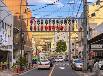 Traffic on city street by buildings against sky