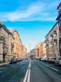 Cars on road by buildings against sky