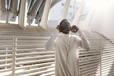 Man listening music with eyes closed near white railing