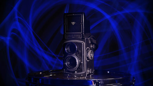 Close-up of illuminated lighting equipment on table against black background