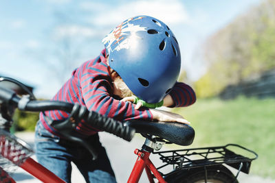 Boy leaning on bicycle at yard on sunny day