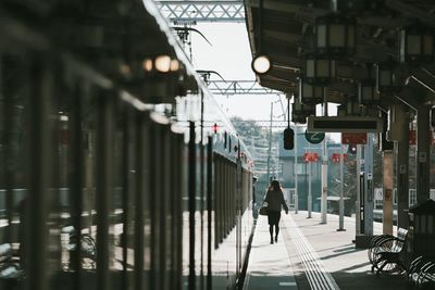 Rear view of man walking on railroad station platform