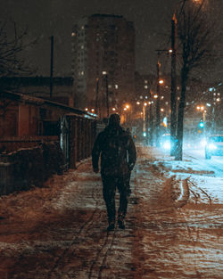 Rear view of man walking in city at night