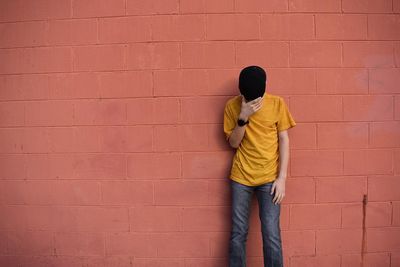 Full length of man standing against red wall