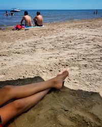 Low section of person lying at beach against sky