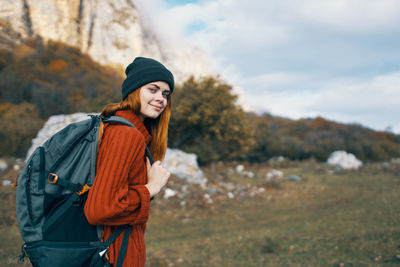 Young woman looking away while standing against sky during winter