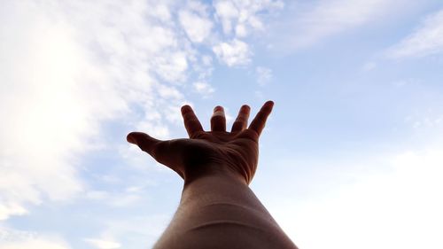 Low angle view of hand against sky