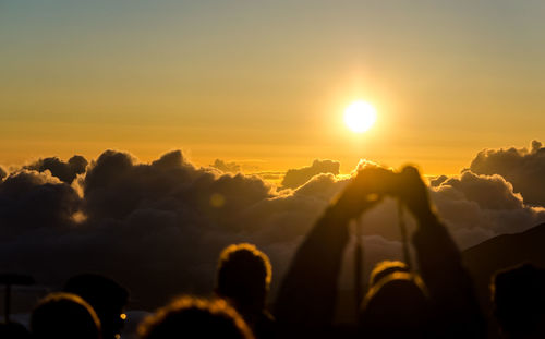 People photographing cloudy sky during sunrise