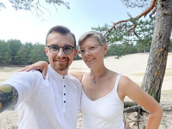 Portrait of young couple standing against trees