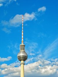 Low angle view of communications tower against cloudy sky