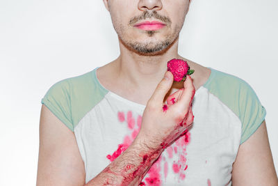 Midsection of man holding strawberry against white background