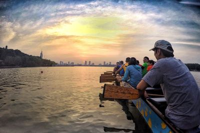 People in boat on sea against cloudy sky during sunset