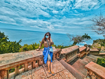 The girl is standing in front of the ocean under the sky 