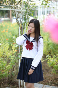 Young woman standing against plants