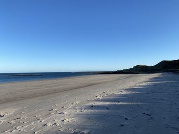 Scenic view of beach against clear blue sky