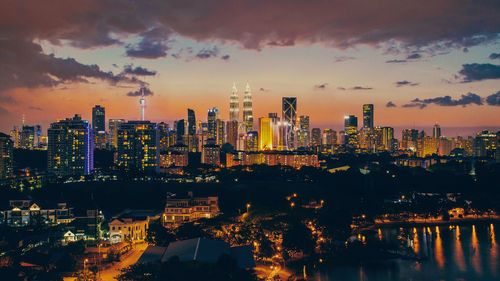 Illuminated cityscape against sky during sunset