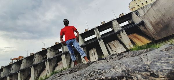 Rear view of man standing by building against sky