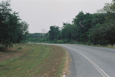 Road amidst trees against clear sky