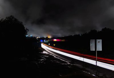 Light trails on road against sky at night