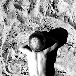 Directly above view of shirtless boy lying on sand