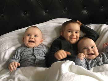 Happy siblings lying on bed