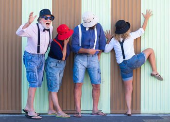 Playful friends standing against wall