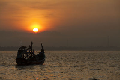 Silhouette boat in sea against sky during sunset