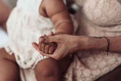 Close-up of hand holding hands on bed