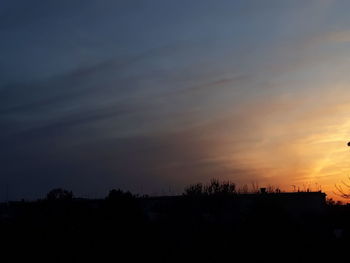 Silhouette trees and buildings against sky at sunset