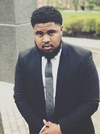 Portrait of young man standing against wall