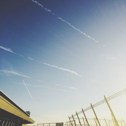 Low angle view of vapor trails against sky on sunny day