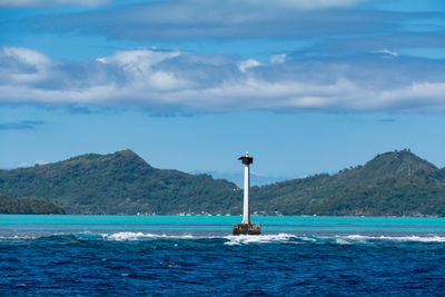 Lighthouse by sea against sky