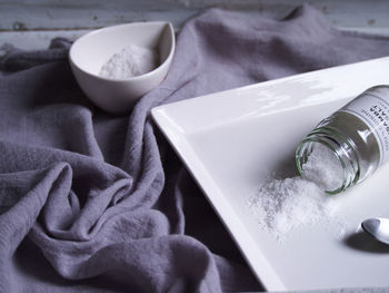 High angle view of salts in bowl and plate on fabric