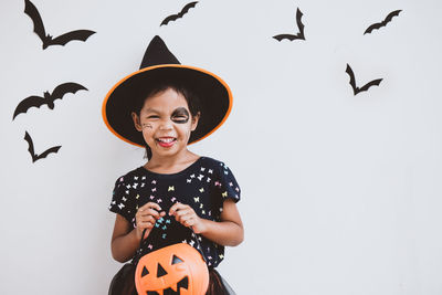 Portrait of cute playful girl with spooky make-up at home during halloween