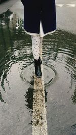 Low section of man standing on puddle