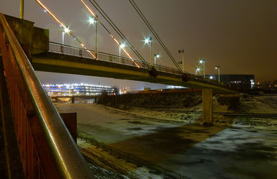 Illuminated bridge over river against sky at night