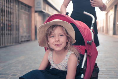 Portrait of cute girl sitting in baby carriage