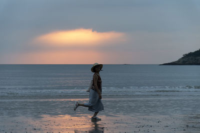 Full length of woman standing on beach during sunset