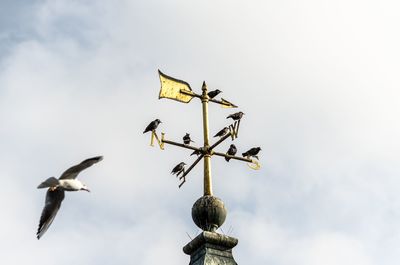 Low angle view of weather vane against sky