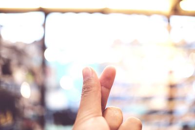 Close-up of human hand against sky