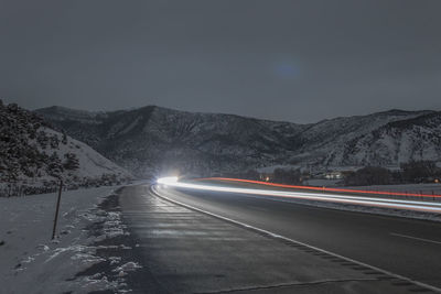 Road passing through illuminated lights at night