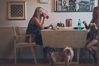 Woman with dog sitting on table at home