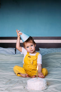 Cute boy sitting on bed at home