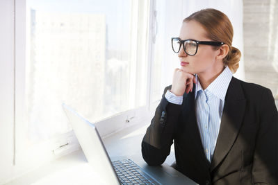 Businesswoman with hand on chin looking away at office