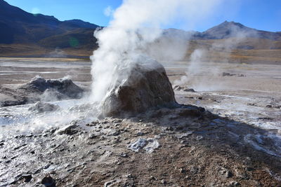 Steam emitting from geyser by rock formation