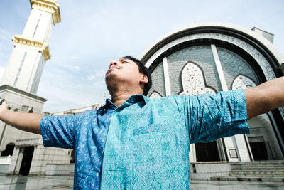 Low angle view of man standing against building in city