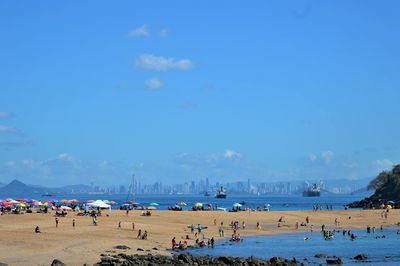 People on beach against blue sky