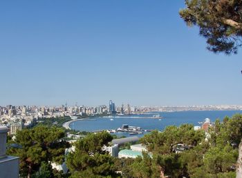 Scenic view of sea and buildings against clear blue sky