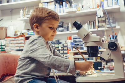 Small boy cleaning mother board with small brush in it lab.