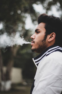 Portrait of young man looking away outdoors